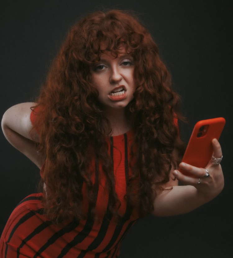 Musical artist Sophie Hunter making a face at the camera and holding a smartphone